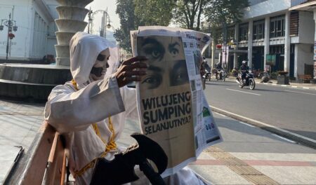 Cosplay membaca koran yang akan mengumumkan pemain baru PERSIB, di Jalan Asia-Afrika Kota Bandung, Rabu, 25 Juni 2025.