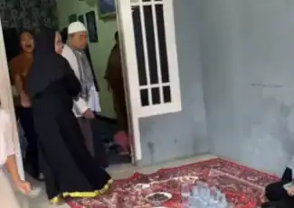 Orang dewasa dan anak-anak berdoa di depan rumah saat acara keagamaan di Indonesia.
