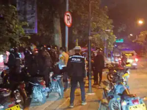 Penegakan hukum parkir motor di malam hari, polisi mengawasi pelanggaran parkir, area jalan kota Indonesia.